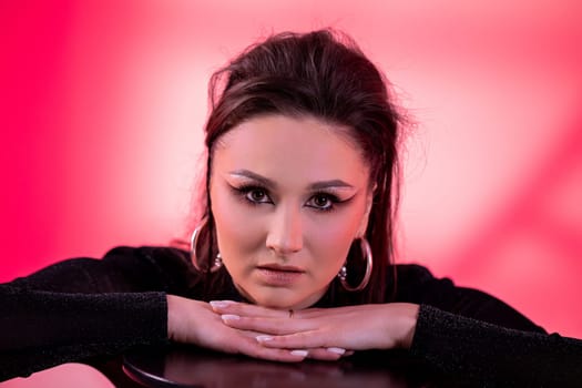 A striking and vivid portrait of a young woman featuring captivating makeup against a lively pink background