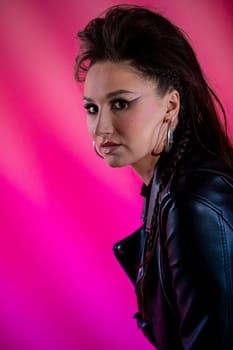 A striking and bold portrait of a confident woman wearing a stylish leather jacket against a vibrant pink backdrop