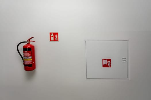 A fire extinguisher and emergency exit signage on a wall, highlighting fire safety in public spaces.