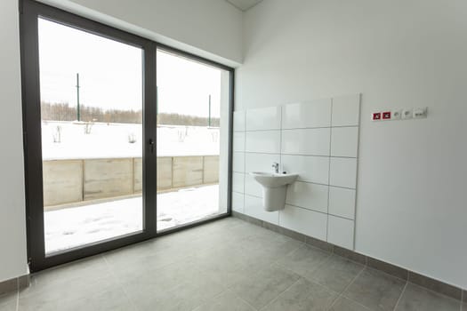 This room is clean and minimalistic, with a sink and expansive windows that showcase views of snowcovered grounds