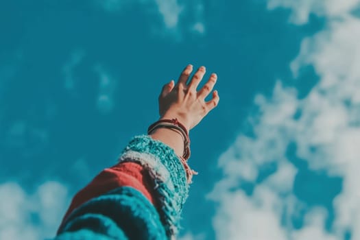 A hand reaching towards a bright blue sky adorned with fluffy clouds symbolizes hope, freedom, and adventure. Ideal for themes of exploration and inspiration.
