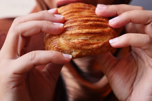 Hands hold a flaky pastry while ready to take a delicious bite.