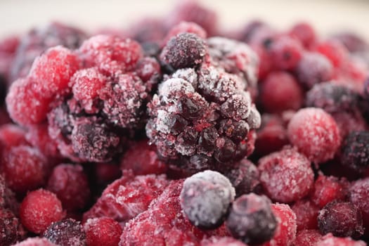 Close-up shot shows an assortment of frozen mixed berries coated with ice.