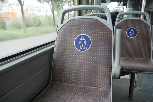 Two vacant seats designated for male passengers in a city bus.