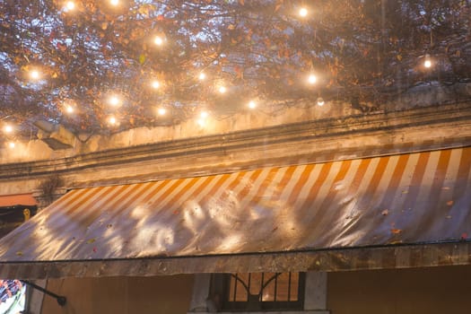 Evening rain creates a serene atmosphere at the cafe with glowing lights.