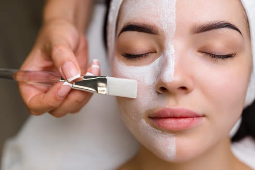 Close-up shot of a woman getting facial treatment with clay mask. Cosmetology and spa. High quality 4k footage