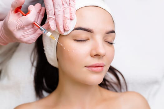 Cosmetologist makes rejuvenating anti wrinkle injections on the face of a beautiful woman. Female aesthetic cosmetology in a beauty salon