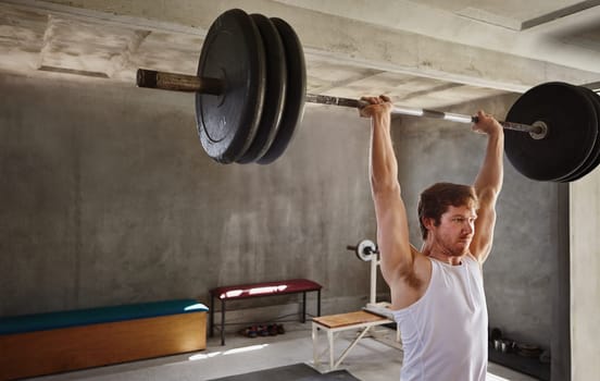 Wide angle shot of a strong man lifting very heavy training weights in a private gym