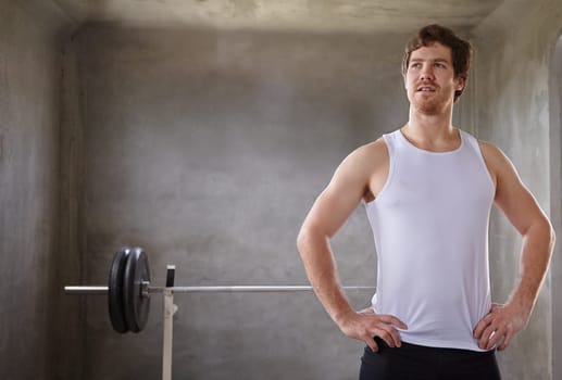 Young fit man looking up with his training weights behind him