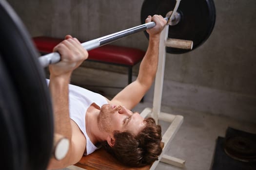 Young man lifting up weights in a private gym