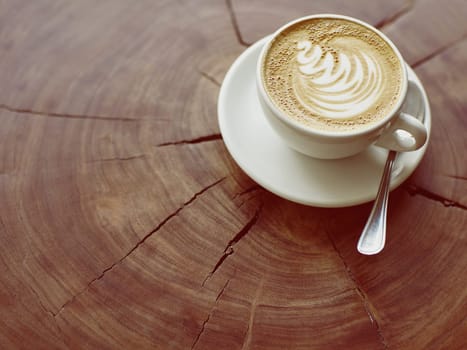 Closeup of a cappucino on a wooden stump with beautiful natural patterns