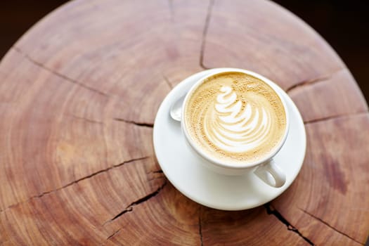 Closeup of a cappucino on a wooden stump with beautiful natural patterns