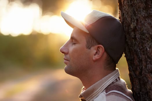 Profile shot of a young man with his eyes closed meditatively in an early morning forest