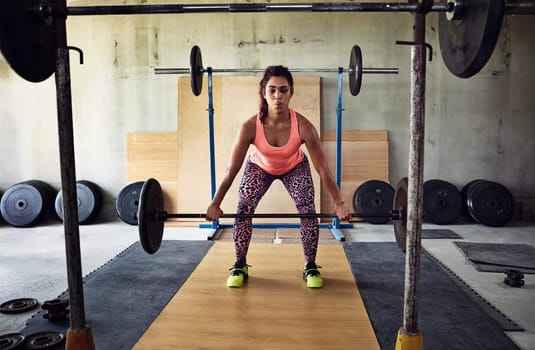 Beautiful woman in a private gym lifting weights in a focussed and serious manner