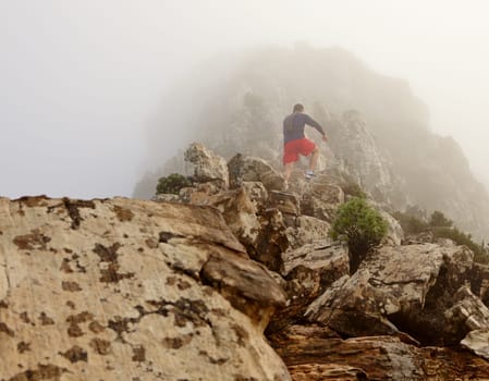 Low angle view of a young man hiking up to the top of a mountain