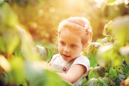Candid shot of a beautiful little girl looking at plants in a garden