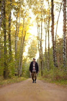 Young man walking along a dirt road in a forest early in the morning