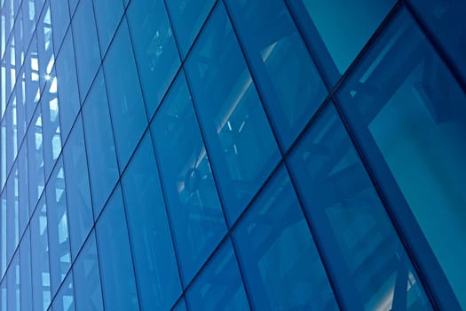 Abstract image of the facade of a modern high rise building covered in reflective plate glass