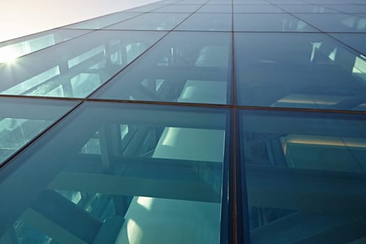 Abstract closeup of the glass-clad facade of a modern building covered in reflective plate glass