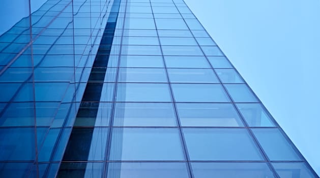 Abstract closeup of the glass-clad facade of a modern building covered in reflective plate glass