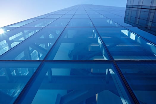 Abstract closeup of the glass-clad facade of a modern building covered in reflective plate glass