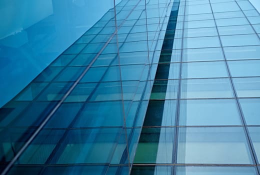 Abstract closeup of the glass-clad facade of a modern building covered in reflective plate glass