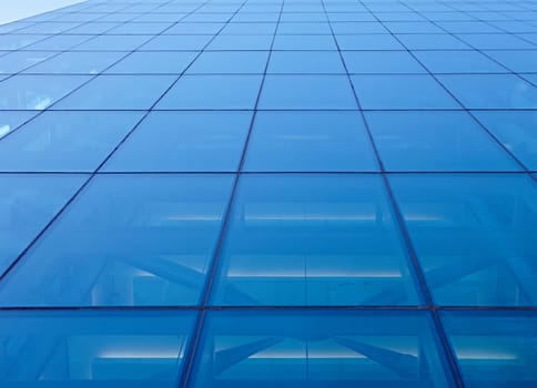 Abstract closeup of the glass-clad facade of a modern building covered in reflective plate glass
