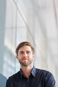 Low angle shot of a handsome executive looking away positively in a modern setting