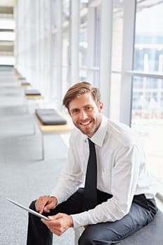 Portrait of a corporate executive smiling while using a digital tablet