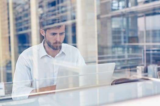 View through a window of a corporate executive working on his laptop