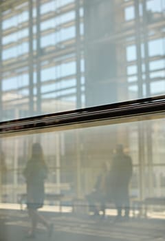 Abstract images of real businesspeople in motion through glass in a busy conference centre