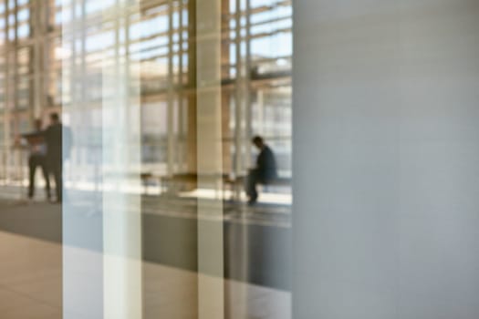 Abstract images of real businesspeople in motion through glass in a busy conference centre