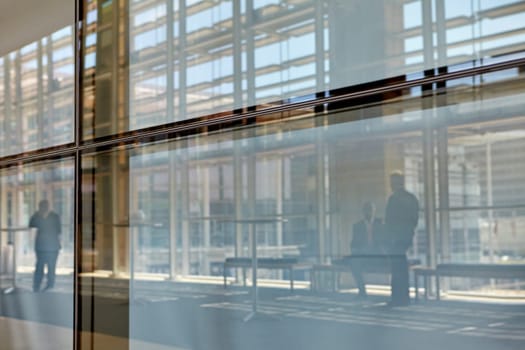 Abstract images of real businesspeople in motion through glass in a busy conference centre