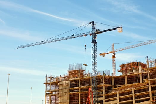 An urban building under contsruction with cranes working to move building materials on site