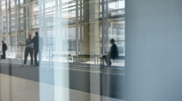 Abstract images of real businesspeople in motion through glass in a busy conference centre