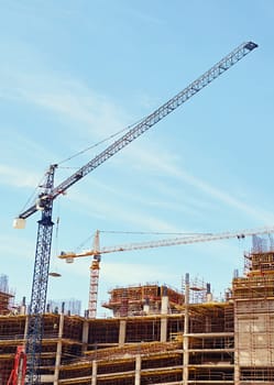 An urban building under contsruction with cranes working to move building materials on site