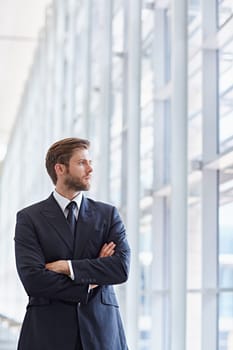 Corporate executive in a modern architectural setting looking confidently out of high rise windows