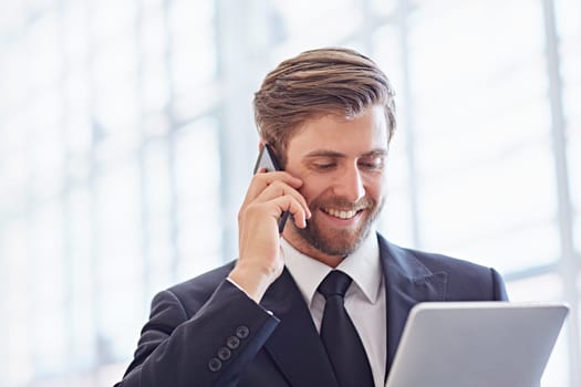 Closeup of a corporate executive smiling while on his phone and looking at a digital tablet