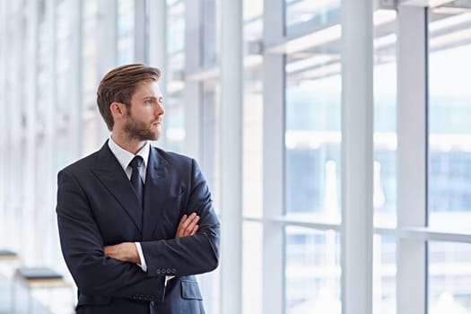 Corporate executive in a modern architectural setting looking confidently out of high rise windows