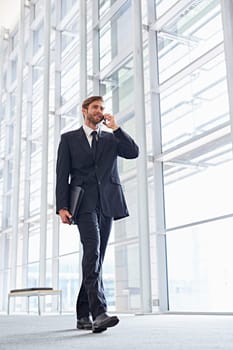 Low angle shot of a corporate executive walking while talking on his mobile phone
