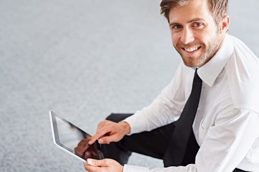 High angle view of a businessman with a digital tablet smiling up at the camera