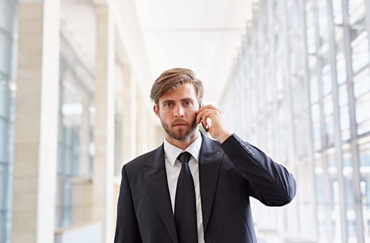 Portrait of a corporate executive looking seriously at the camera while listening on his phone