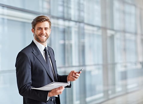 Corporate executive smiling at the camera while holding his phone and a notes