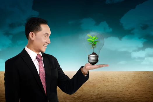 Business person holding light bulb with plant inside. Green energy concept