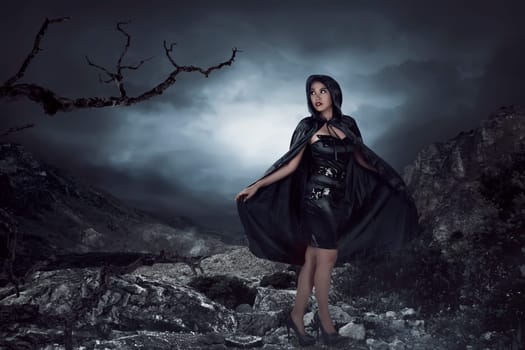 Asian woman wearing black costume, she standing on the rock with mountain background and black cloud