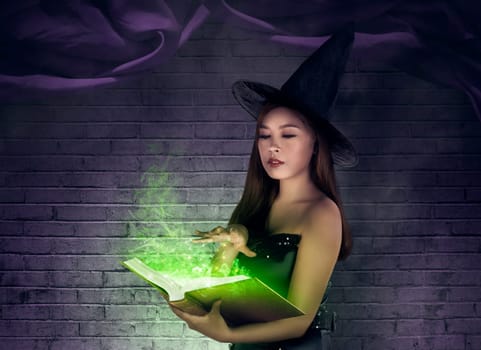 Asian sexy witch creating a spell at the book with magical items
