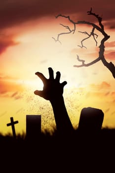 Silhouette corpse raising hands from his grave on the cemetery at sunset