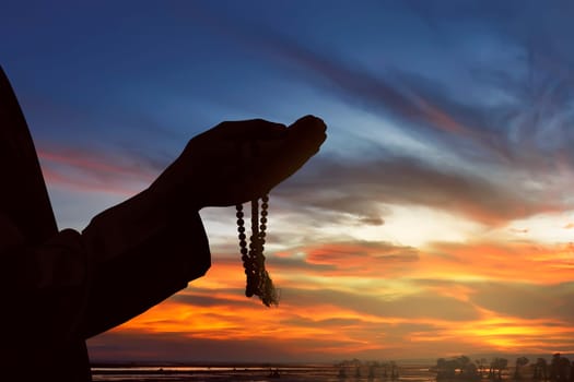 Image of silhouette hand man praying with sunset background