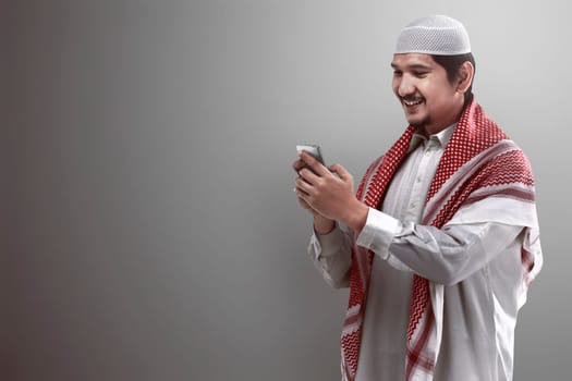 Muslim man holding cellphone and typing on the phone