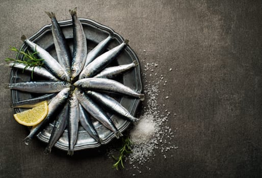 Fresh raw sardines with salt and herbs on rustic background